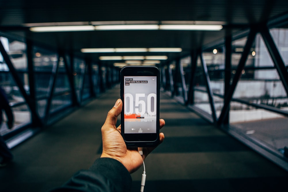 person holding black smartphone while standing on bridge