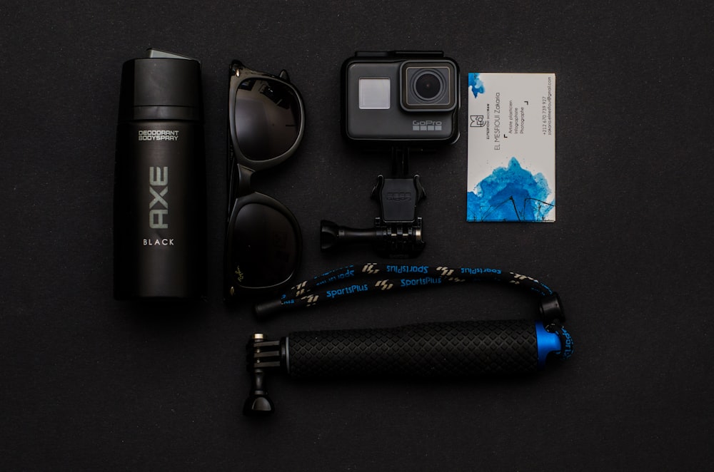 flat-lay photography of action camera, sunglasses, and Axe body spray