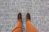 A casual yet elegant outfit featuring khaki pants and sleek leather shoes on a cobblestone street.