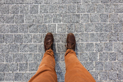 A casual yet elegant outfit featuring khaki pants and sleek leather shoes on a cobblestone street.