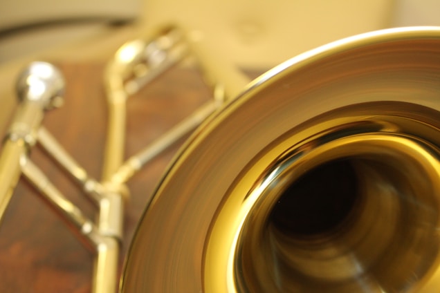 A close-up shot of a gleaming brass trumpet with rich gold accents, resting on a black velvet cloth under soft light.