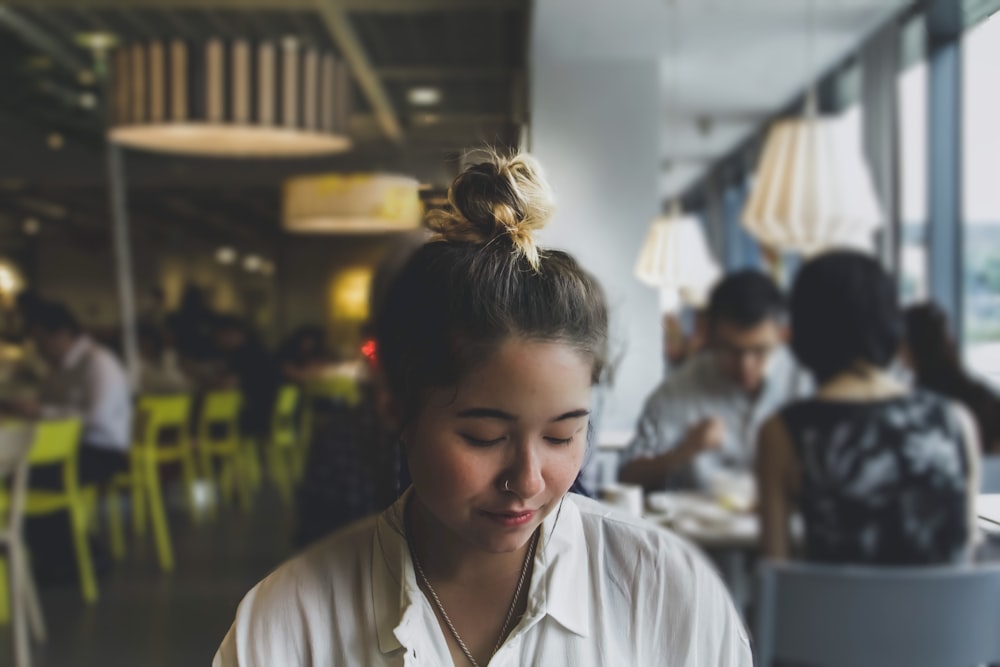 Menschen, die hinter einer Frau essen, die im Restaurant auf einem Stuhl sitzt