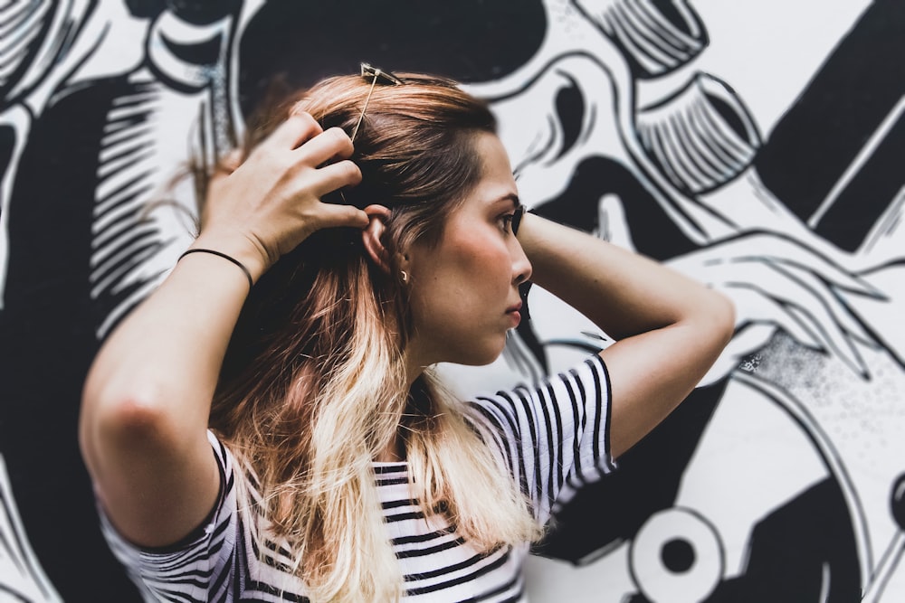 woman in black and white striped top standing near wall with graffiti