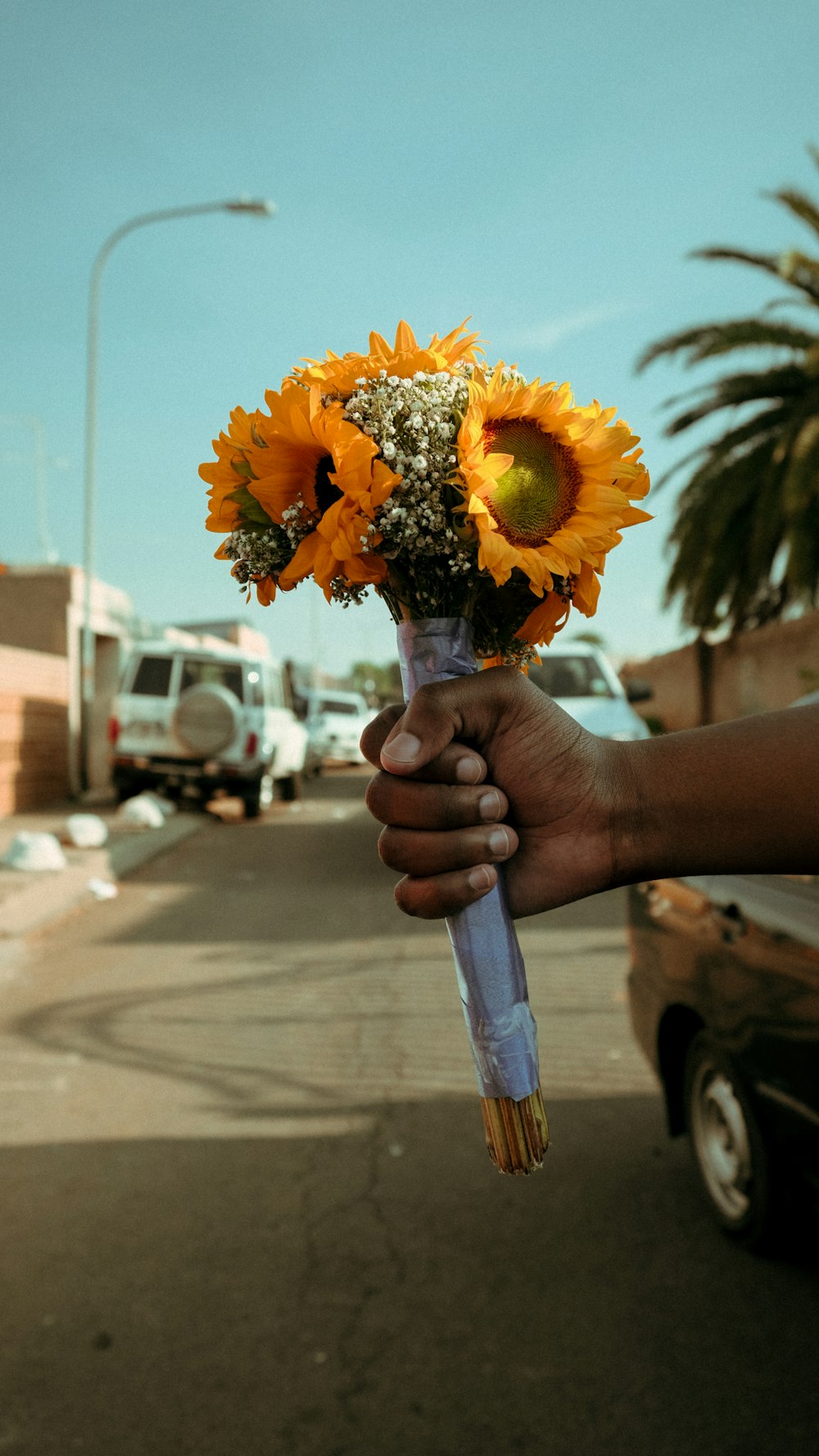 persona con la mano sosteniendo el ramo de girasoles