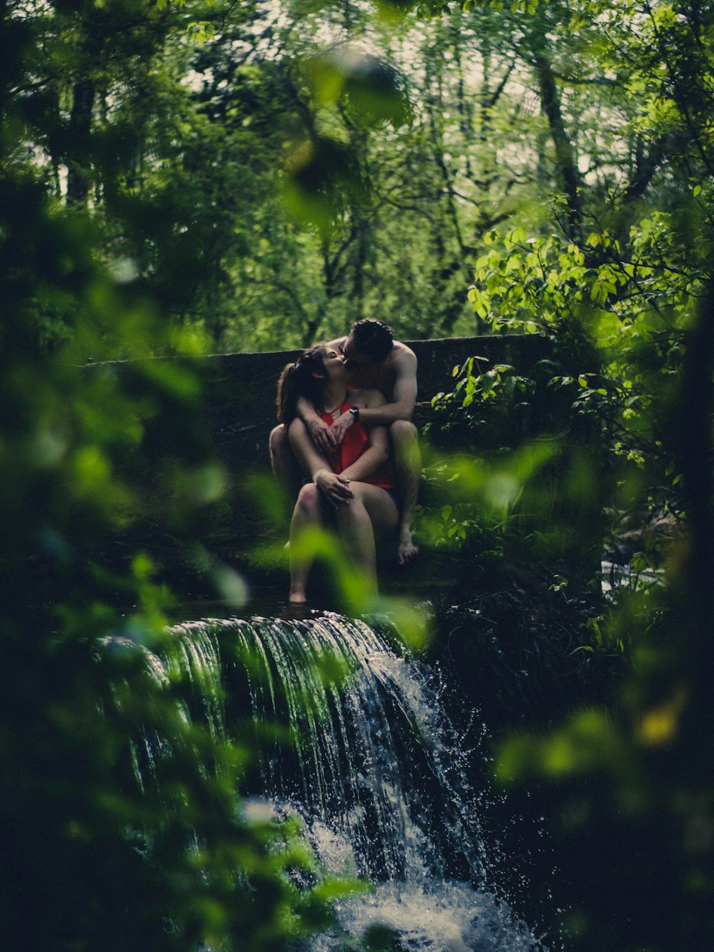 coppia che si bacia sulle cascate nella foresta durante il giorno