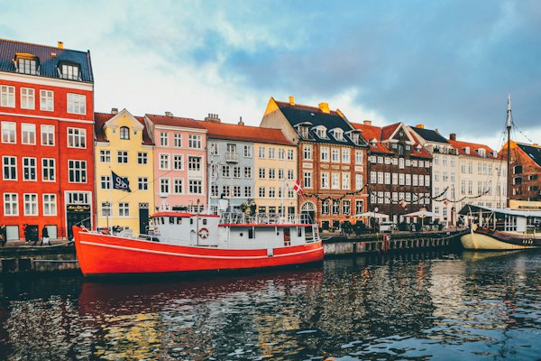 A bright red boat moored in Nyhavn canal before colorful historic buildings in Copenhagen
