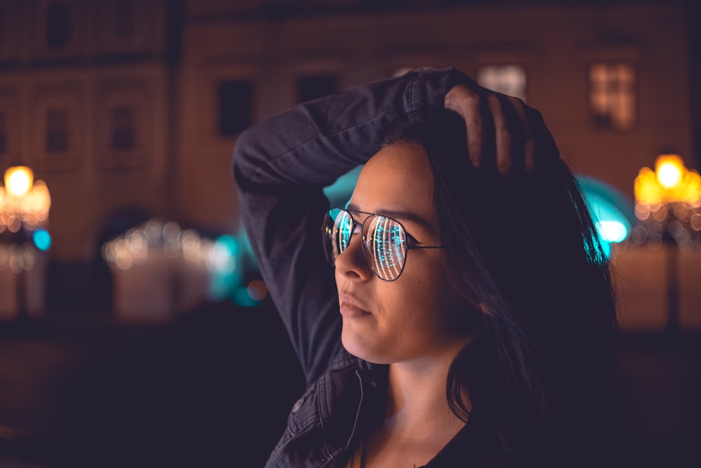 woman wearing aviator eyeglasses with black frame holding head