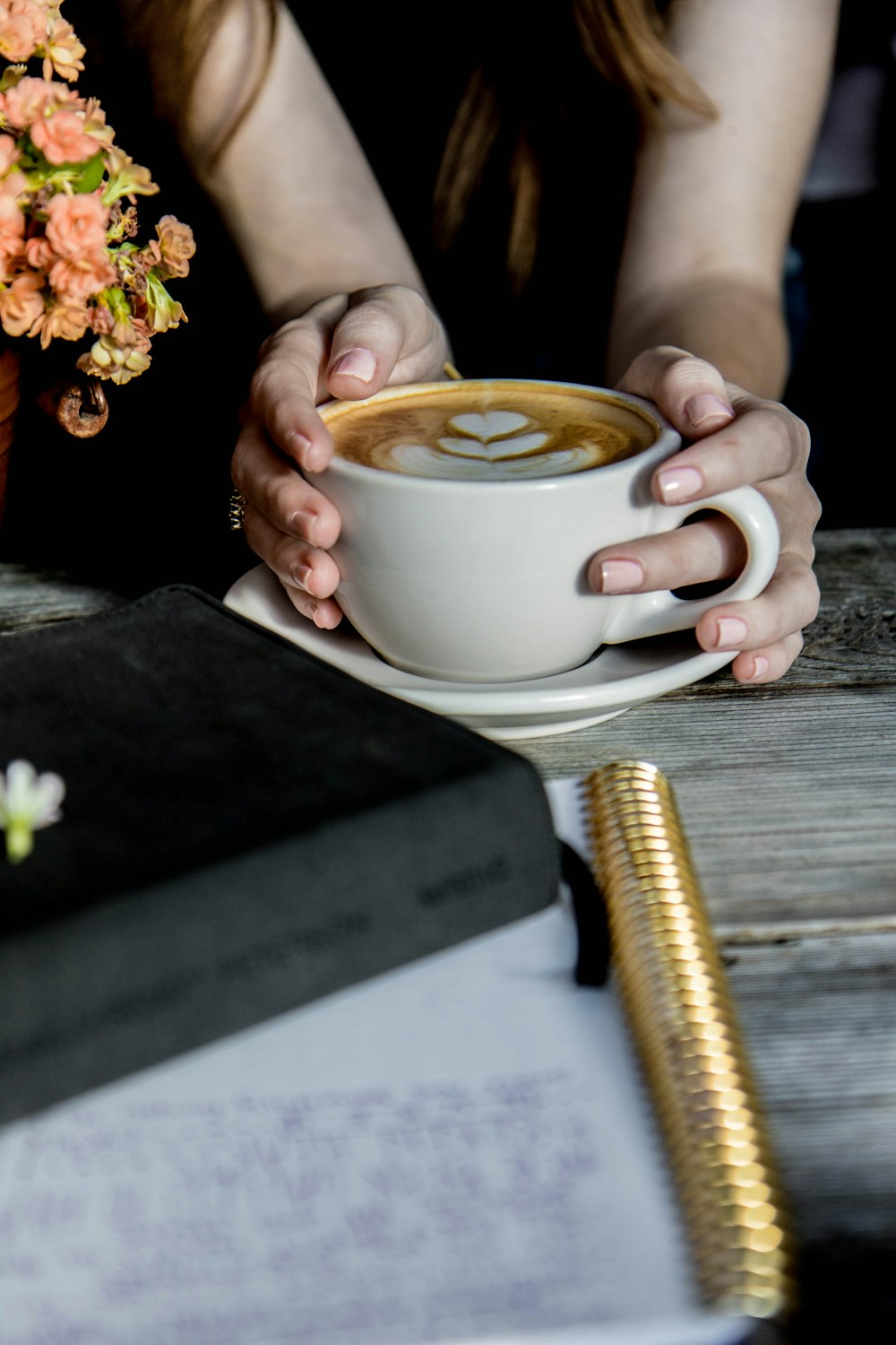 personne tenant une tasse en céramique beige remplie d’un liquide brun