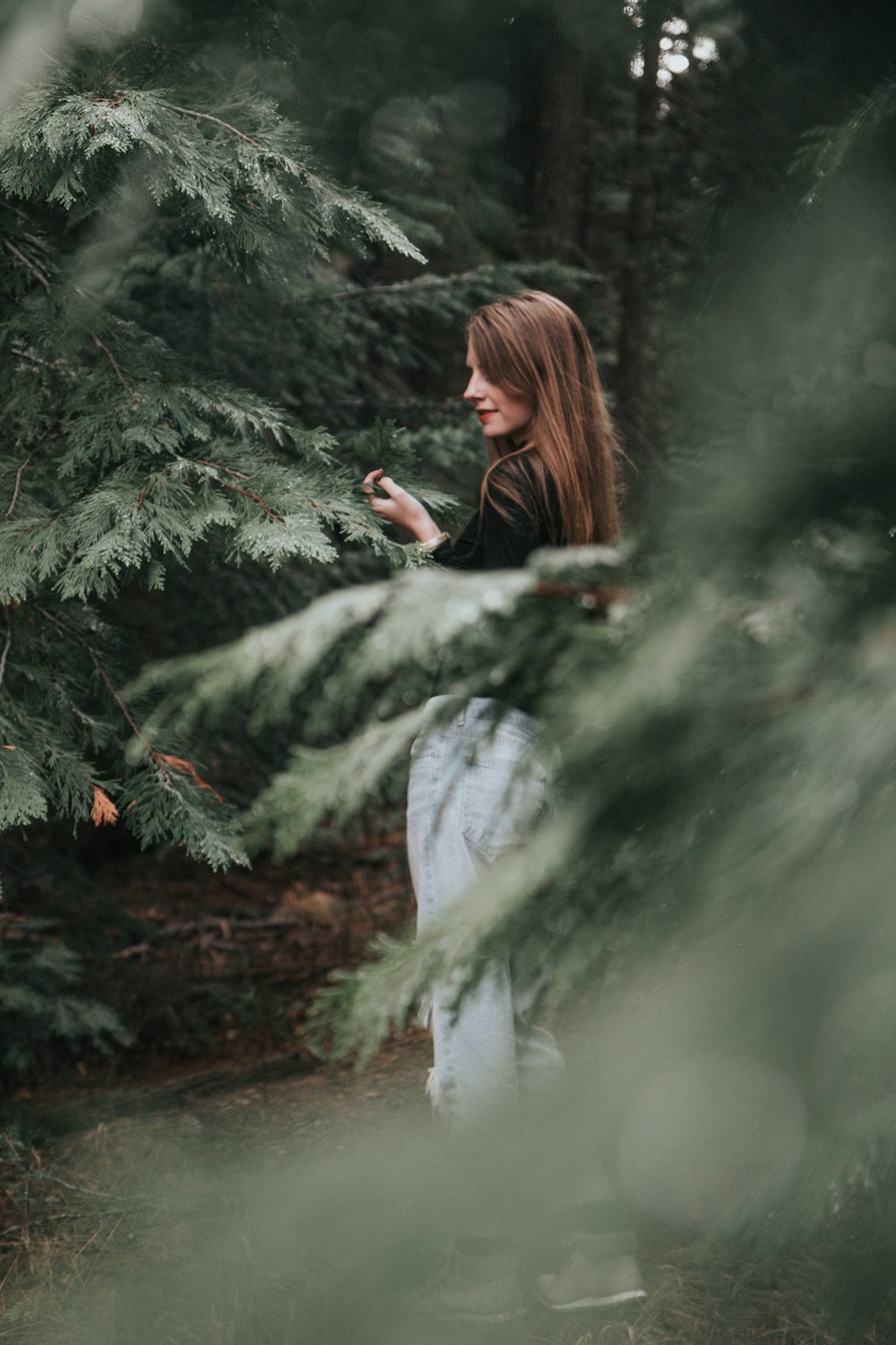selective focus photography of woman standing between trees
