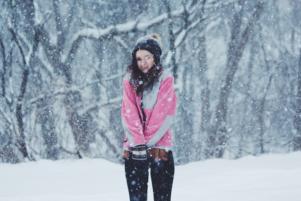 Frau in rosa Jacke steht auf Schneeboden