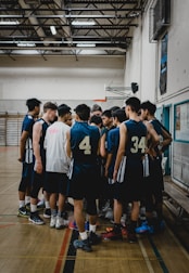 A group of players listening attentively during a team meeting in the gym.