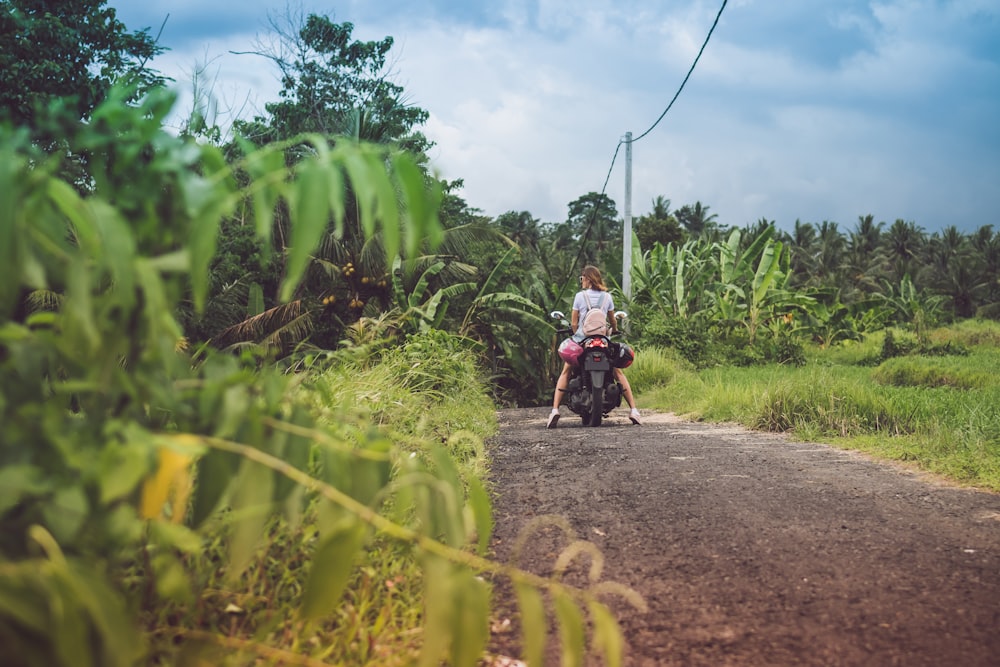 mulher na motocicleta na estrada sob o céu nublado durante o dia