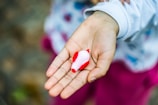 A close-up of a child’s hands gently holding a smooth, earth-toned wooden animal figurine.