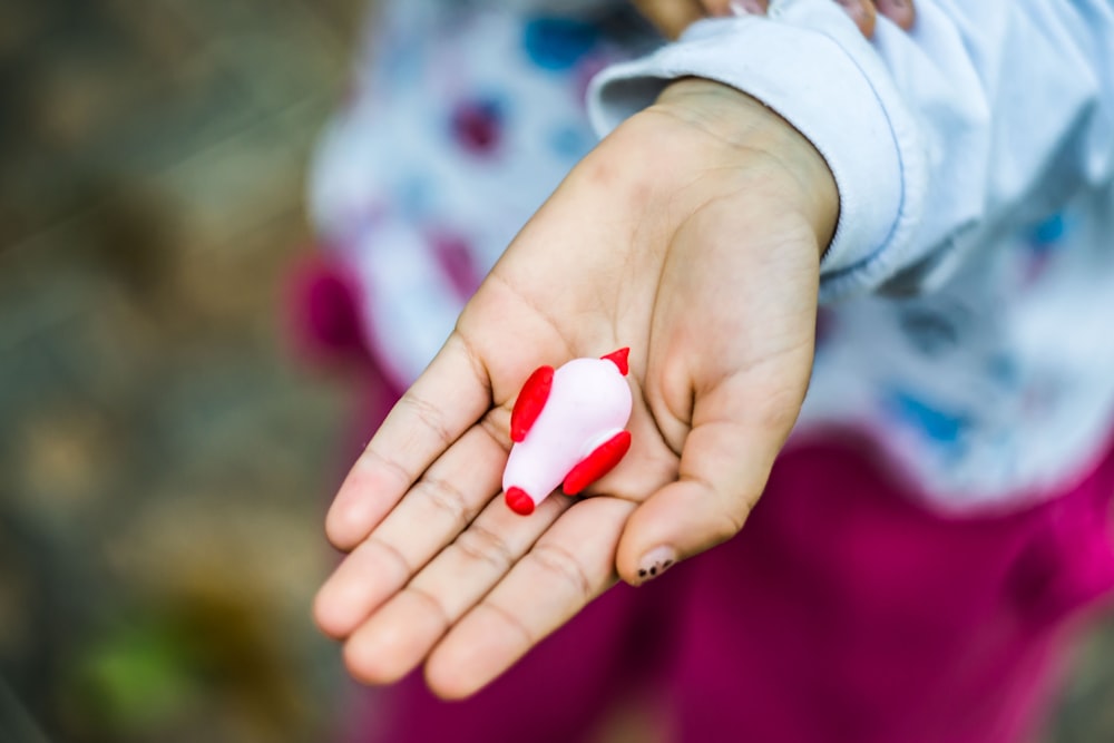 red and white bird toy on left person's palm