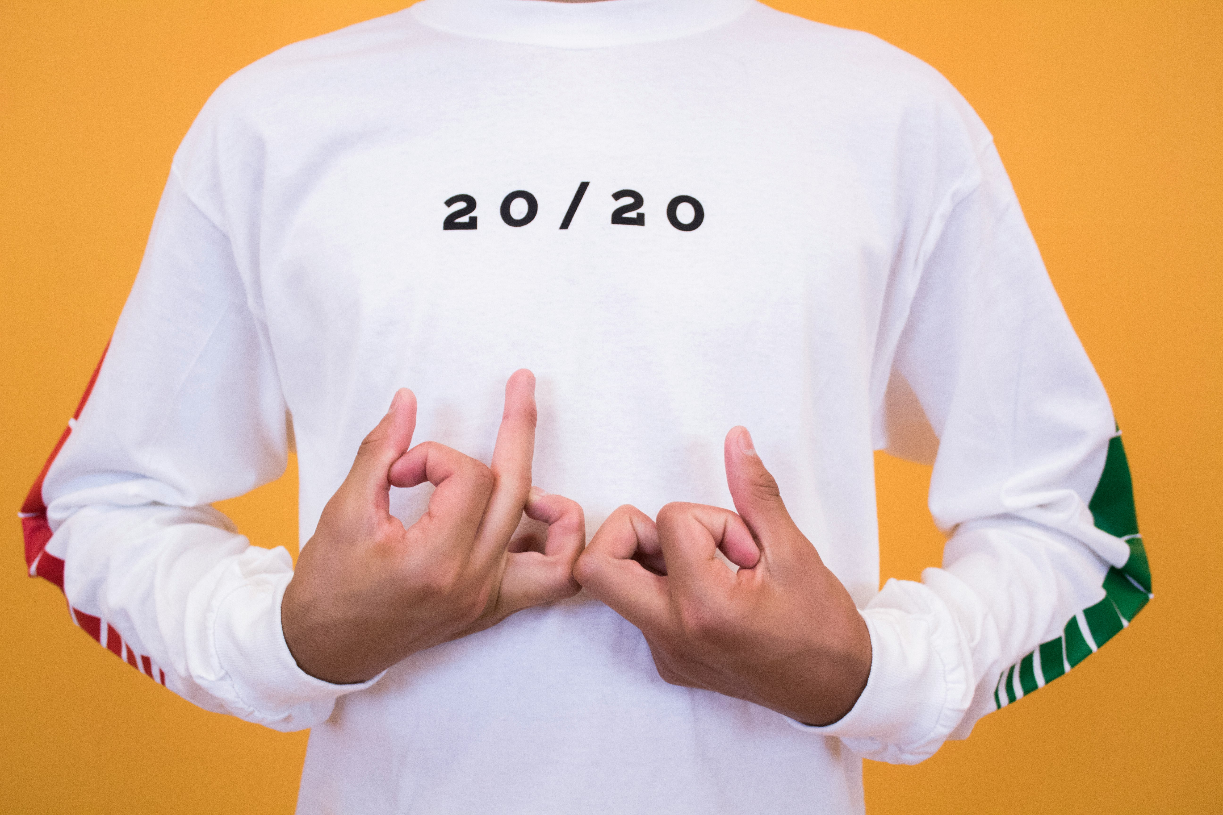 man in white and black 20/20 printed crew-neck sweatshirt making handsigns