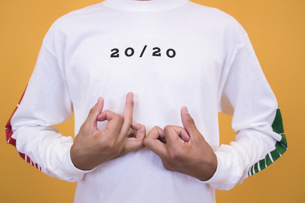 man in white and black 20/20 printed crew-neck sweatshirt making handsigns