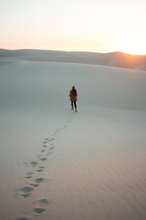 A solitary figure walking away from eight golden cups under a twilight sky, symbolizing introspection and moving on.