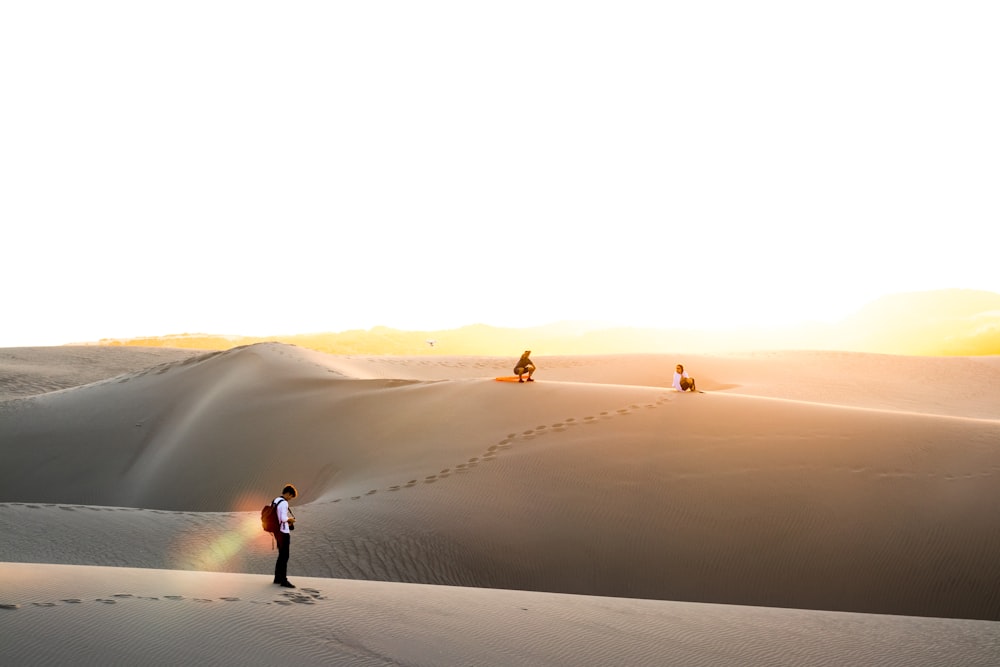 three men on desert under clear blue sky during daytime