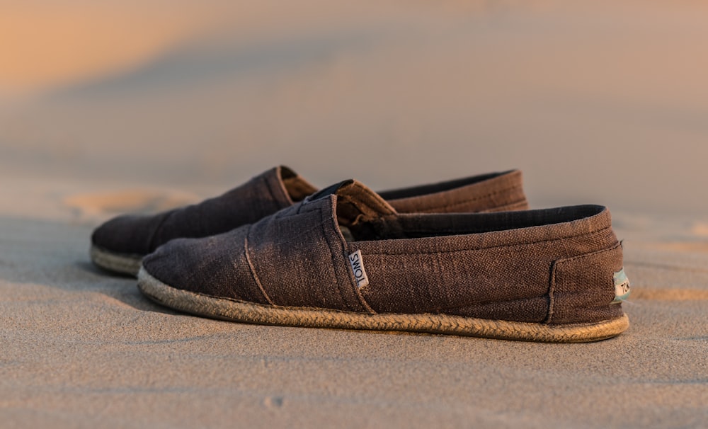 pair of brown Toms loafers on brown sand