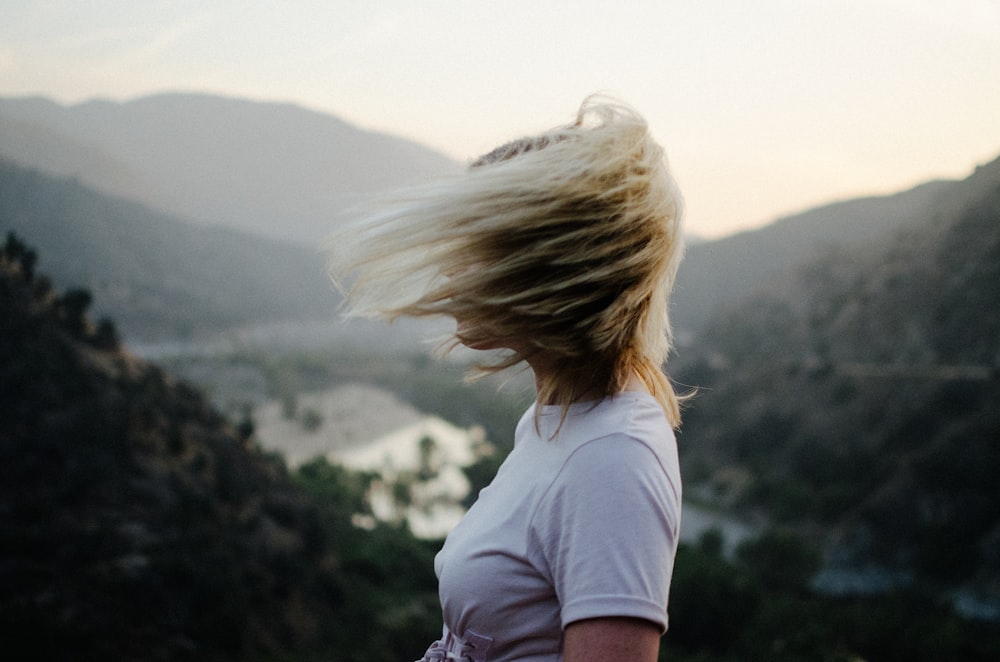 woman wearing white t-shirt near mountain during daytime