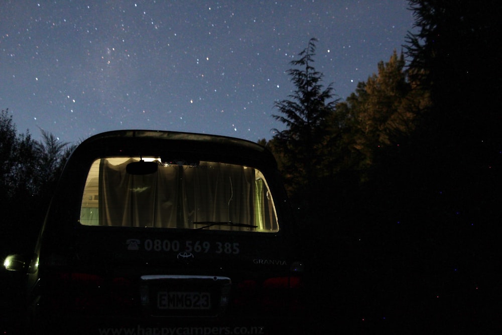 black vehicle parked near trees during nighttime