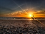 silhouette of person walking on shore during golden hour