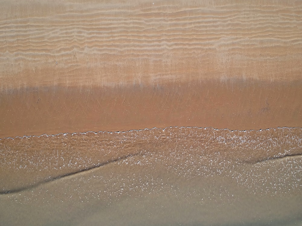 a sandy beach with a wave coming in to shore