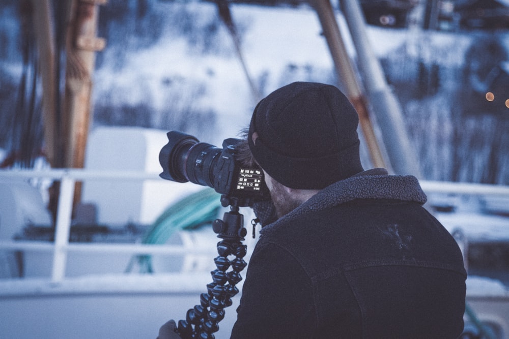 man in black jacket holding DSLR camera