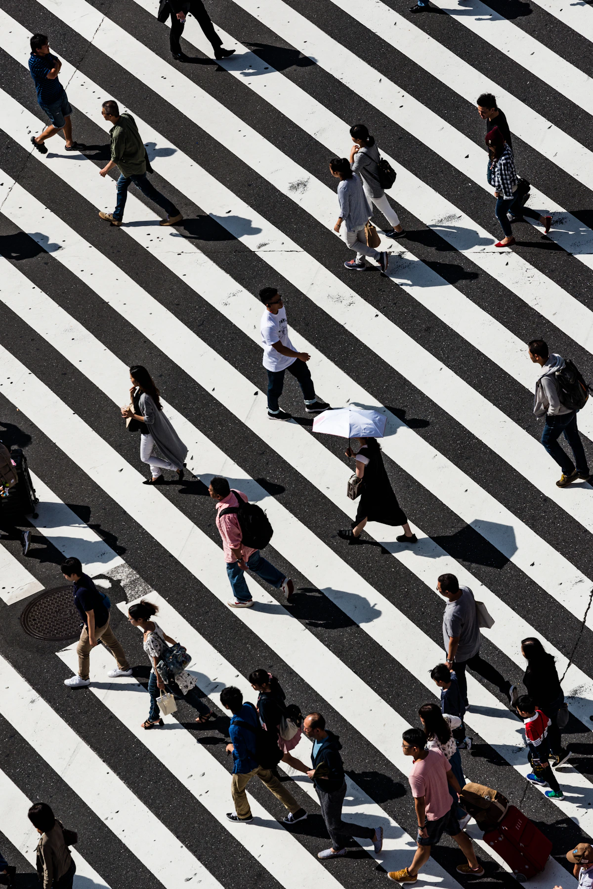 Pedestrians walking across a striped city crosswalk