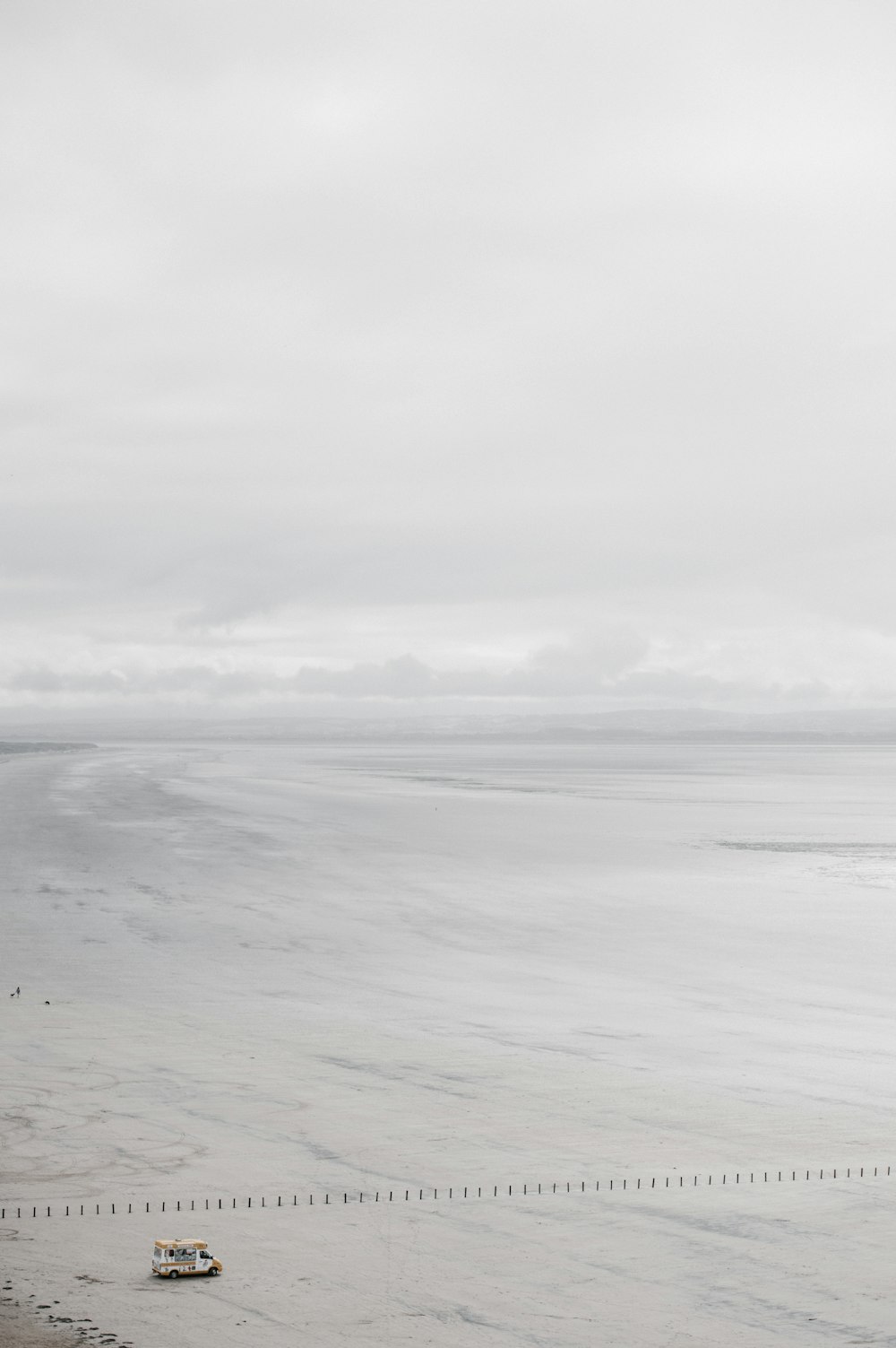 white and yellow RV on seashore under white sky during daytime