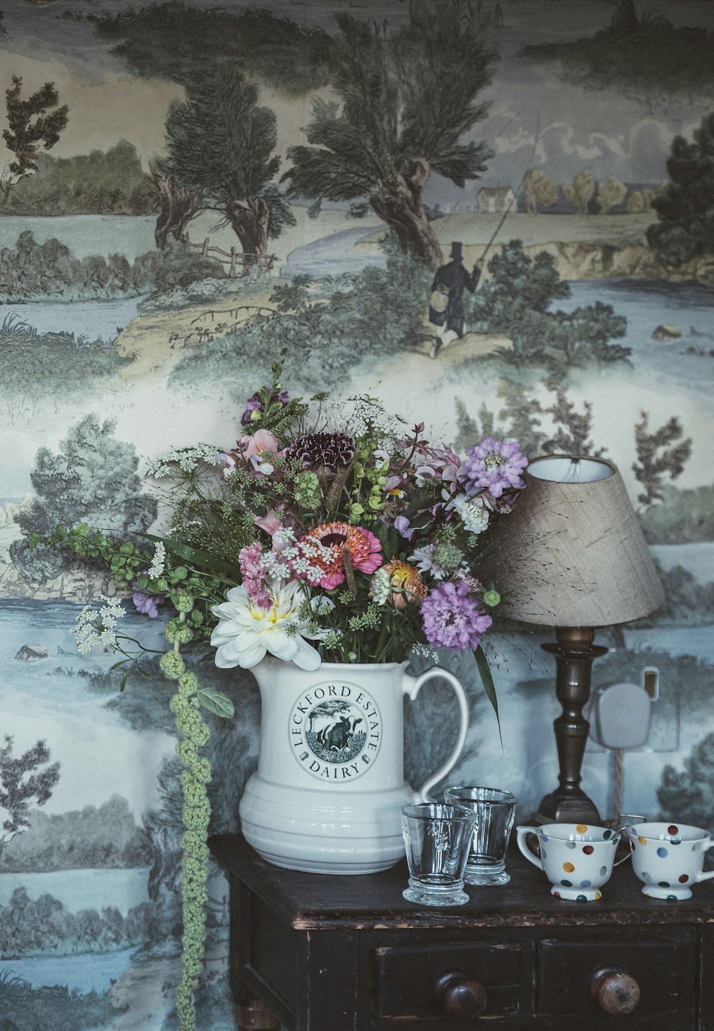 weißer Keramikkrug mit Blumen auf braunem Holztisch
