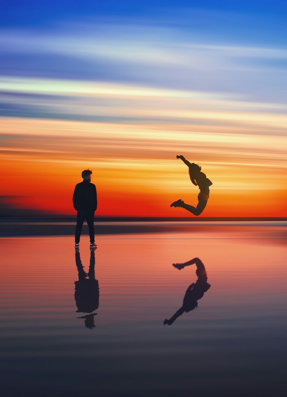 man near woman jumping near body of water