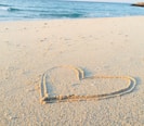 heart drawn on sand during daytime