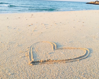 heart drawn on sand during daytime