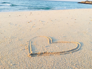 heart drawn on sand during daytime