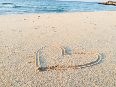 heart drawn on sand during daytime profound teams background