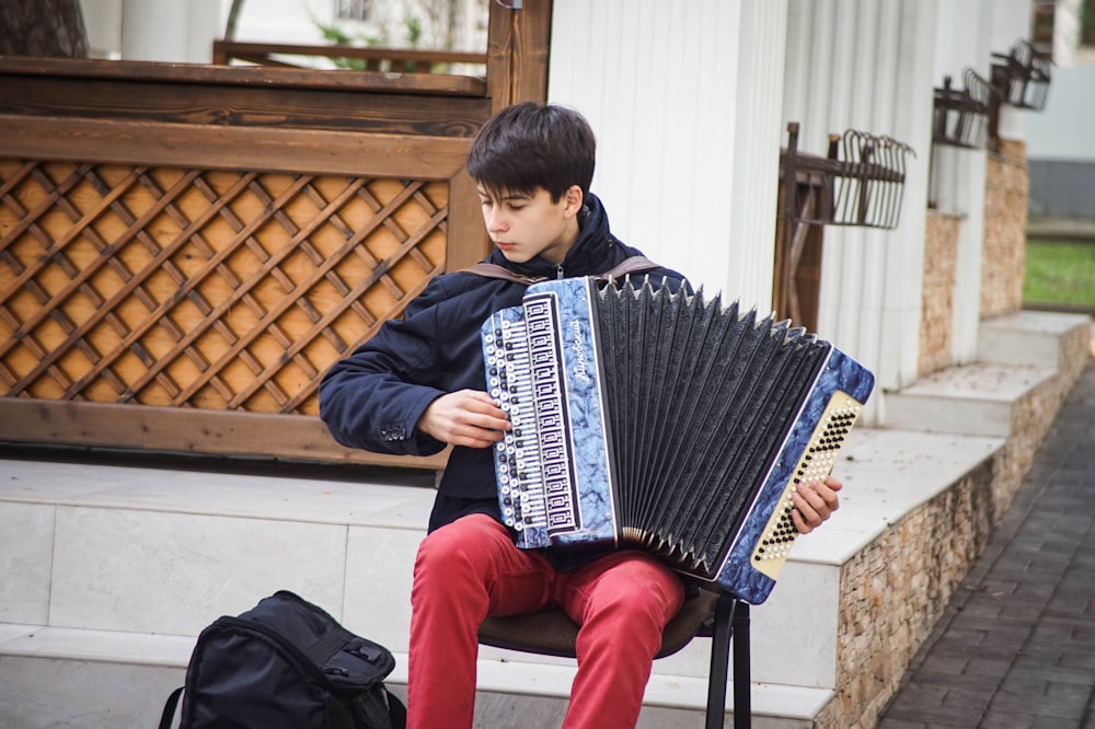 man playing blue accordion during daytime