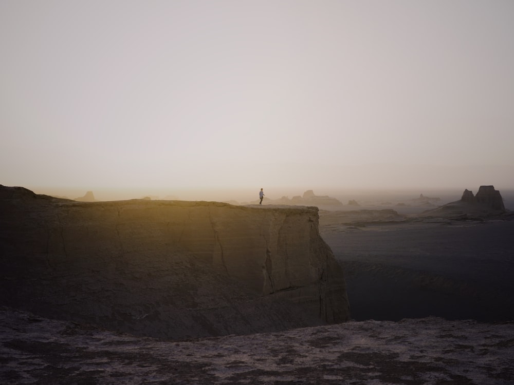 personne debout sur la falaise sous le ciel blanc