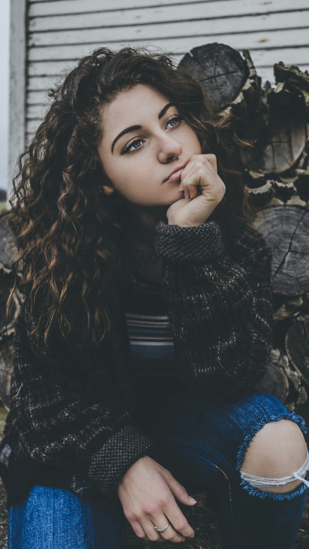 woman in black sweater and blue distressed bottoms shallow focus photography