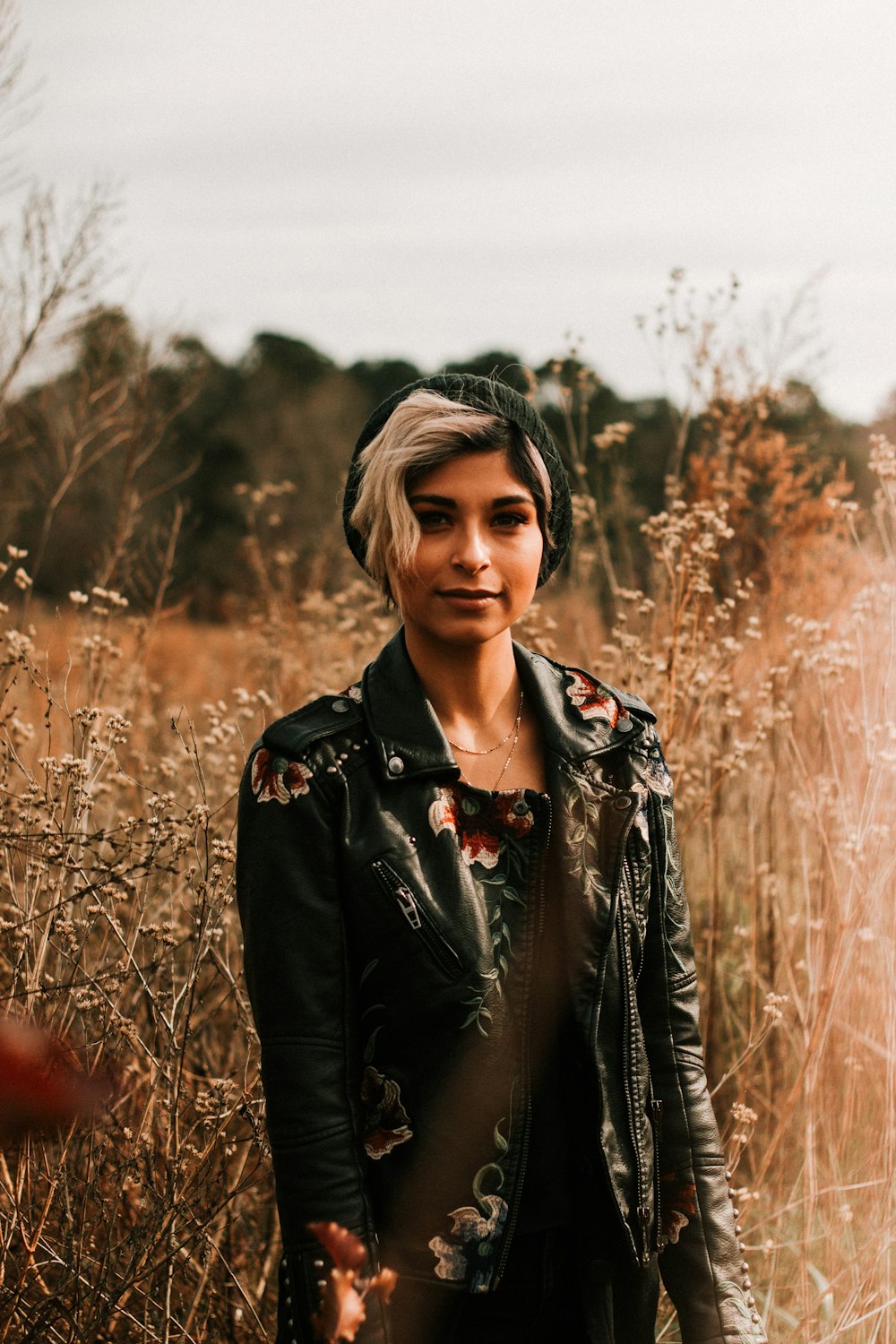 standing woman wearing leather jacket at the field during day