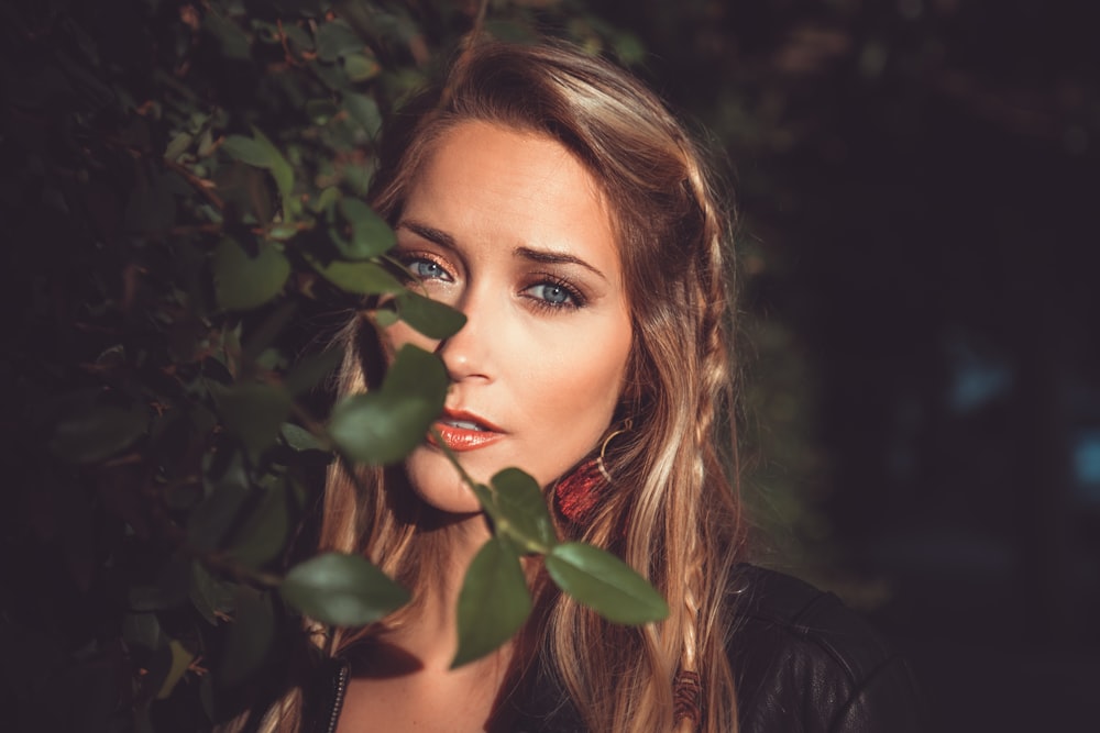 woman behind green leaf in selective focus photography