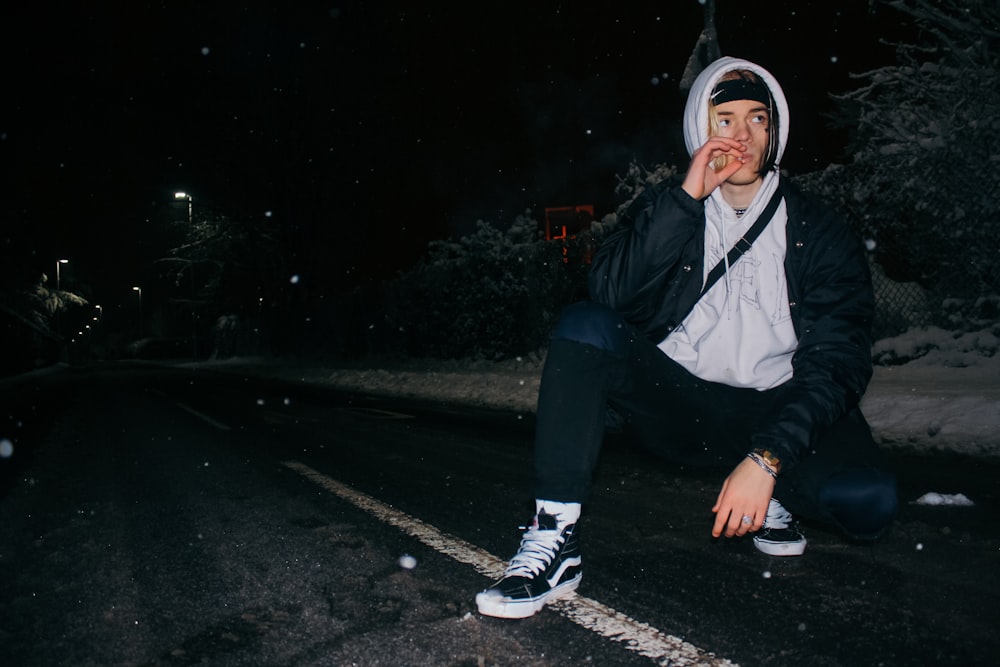 man sitting while smoking near tree