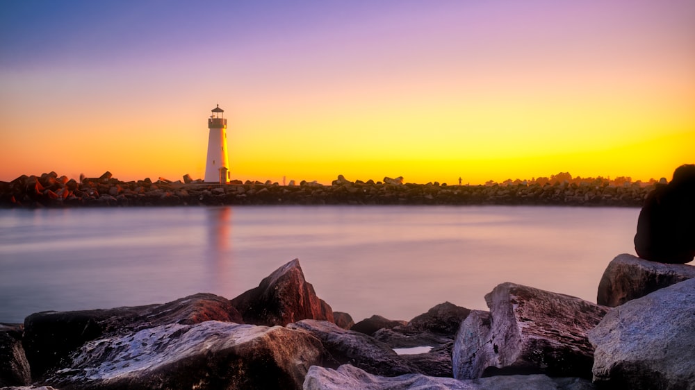 Photo de rochers à côté d’un plan d’eau avec vue sur le phare