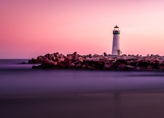 white lighthouse on rocky seashore