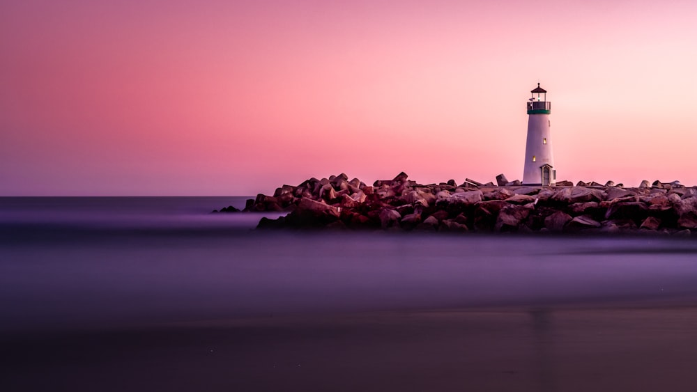 Faro blanco en la orilla rocosa del mar