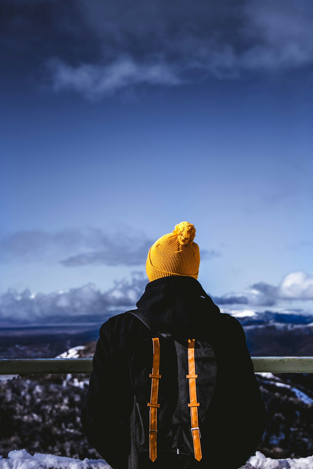 homme en veste noire sous un ciel bleu nuageux