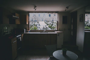 Modern kitchen corner with beige cabinetry and a small bird perched on a windowsill