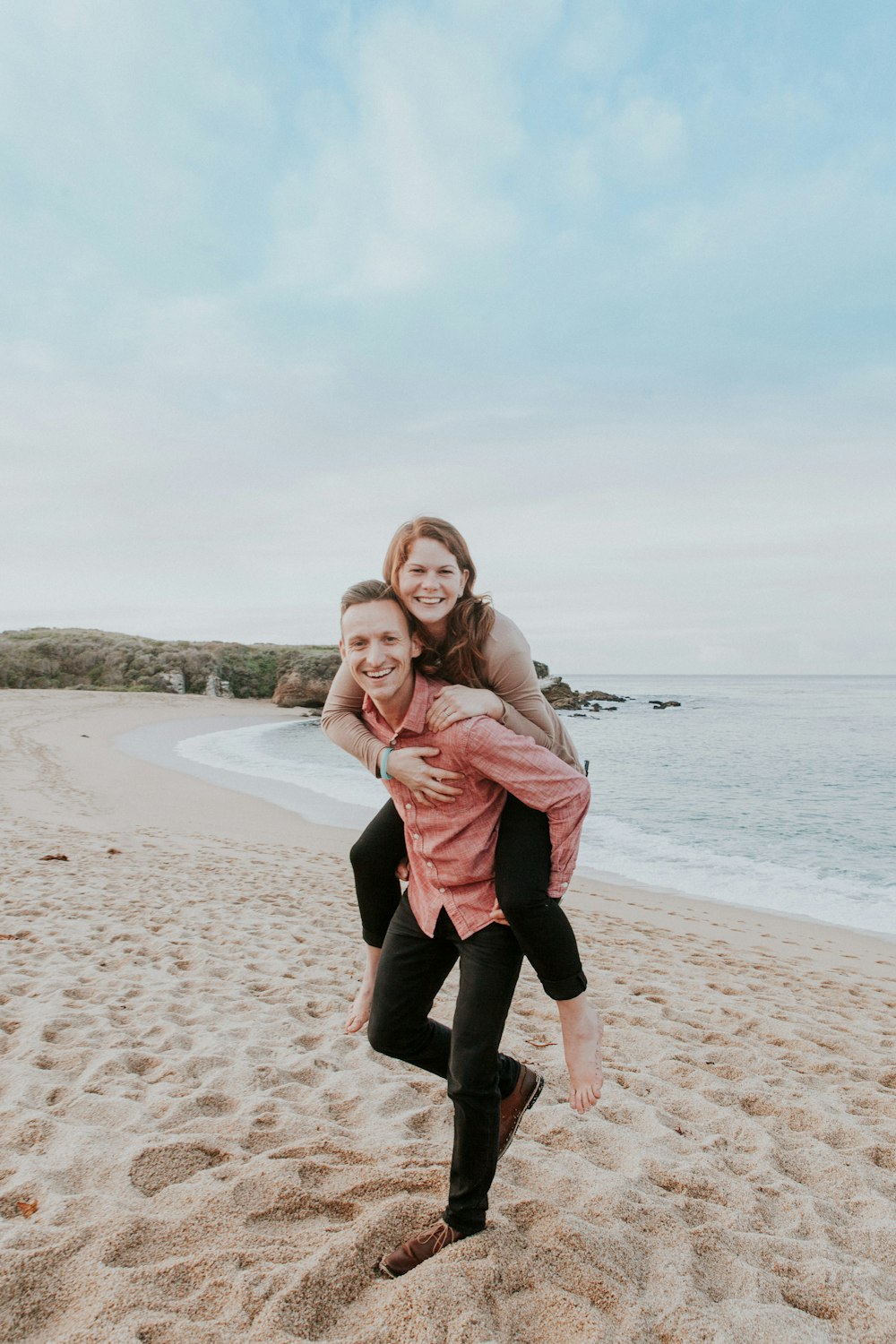 man carrying woman beside seashore