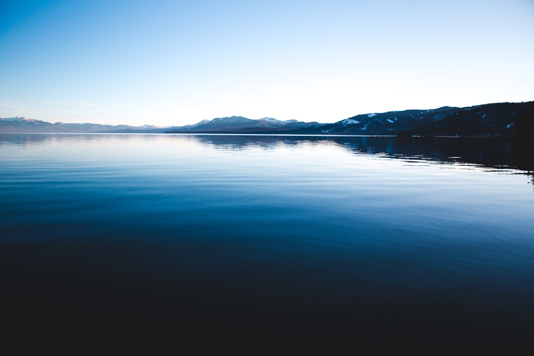 body of water near mountain during daytime