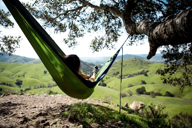 Guests relaxing in hammocks surrounded by lush greenery and gentle hills.